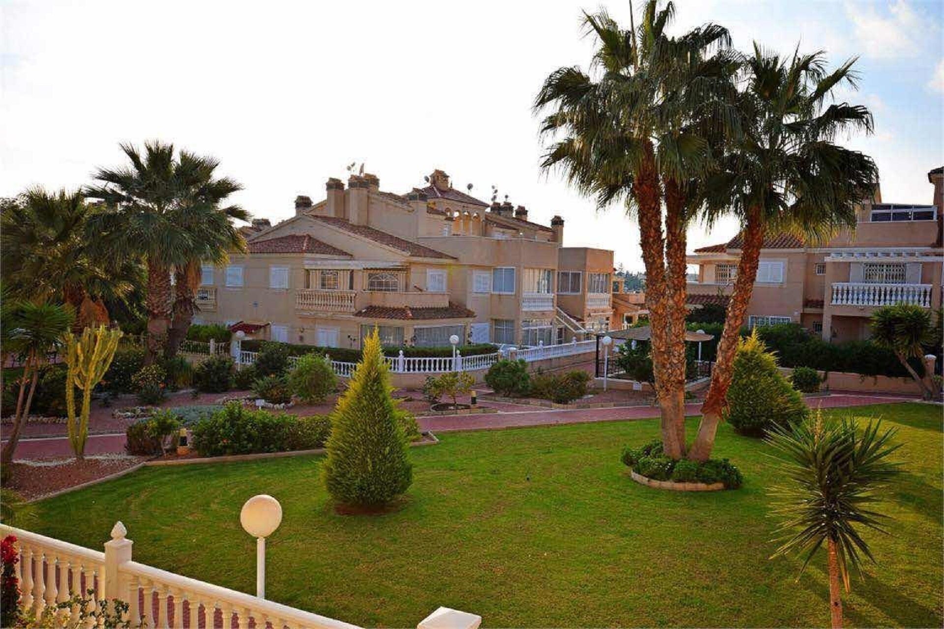 Ein mehrstöckiges Hotel mit Balkonen, umgeben von Palmen und gepflegten Rasenflächen.
