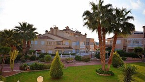 A multi-story hotel with balconies, surrounded by palm trees and well-maintained lawns. - Cosy flat on second floor with large pool (Orihuela)
