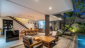Uma sala de estar moderna com escada, assentos, piscina e cozinha.