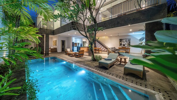 Uma área interna de piscina moderna com escadaria, cadeiras de descanso e espaço para refeições.