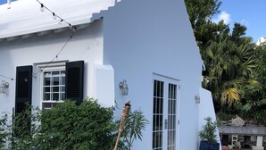 A white building with a sloped roof, a brick pathway, and potted plants. - Wild Bird, Paget - Pool, Twizy charger, Kitchenette -  non smoking property (Paget)