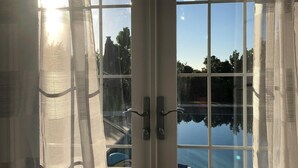 A glass door with a view of a swimming pool and a stone pathway. - Wild Bird, Paget - Pool, Twizy charger, Kitchenette -  non smoking property (Paget)
