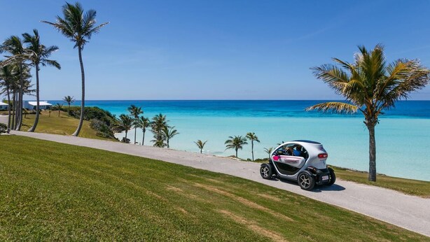 A golf cart on a paved path with a view of the ocean and palm trees. - Wild Bird, Paget - Pool, Twizy charger, Kitchenette -  non smoking property (Paget)