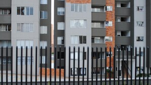 A multi-story residential building with balconies and a fenced area with two hot tubs.