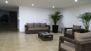 A living room with a sofa, armchairs, a coffee table, and potted plants.