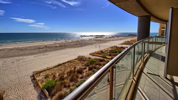 A beach view from a balcony with a glass railing, sandy beach, and ocean. - Ocean View 1BR Private balcony OAKS PIER (Glenelg)