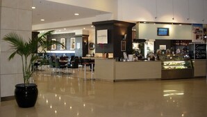 A modern lobby with a reception desk, seating area, and a food counter. - Ocean View 1BR Private balcony OAKS PIER (Glenelg)