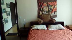 A bedroom with a bed, pillows, a chair, a nightstand, a lamp, and a tapestry on the wall. - Private Apartment in Quito's Best Neighborhood (Quito)