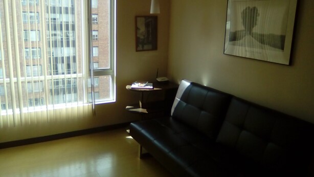 A room with a black leather sofa, a small table with a lamp, and a framed picture on the wall. - Private Apartment in Quito's Best Neighborhood (Quito)