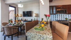 A modern kitchen with a granite countertop, stainless steel appliances, and a dining area with wicker chairs and a table set for two. - Beachfront right on Los Muertos beach (Amapas)