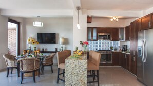 A modern kitchen with dark wooden cabinets, a stainless steel refrigerator, and a granite countertop. - Beachfront right on Los Muertos beach (Amapas)