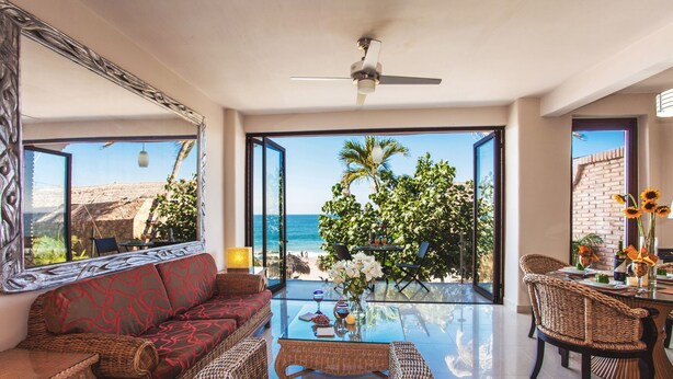 A spacious living area with a large glass table, wicker furniture, and a view of the beach. - Beachfront right on Los Muertos beach (Amapas)