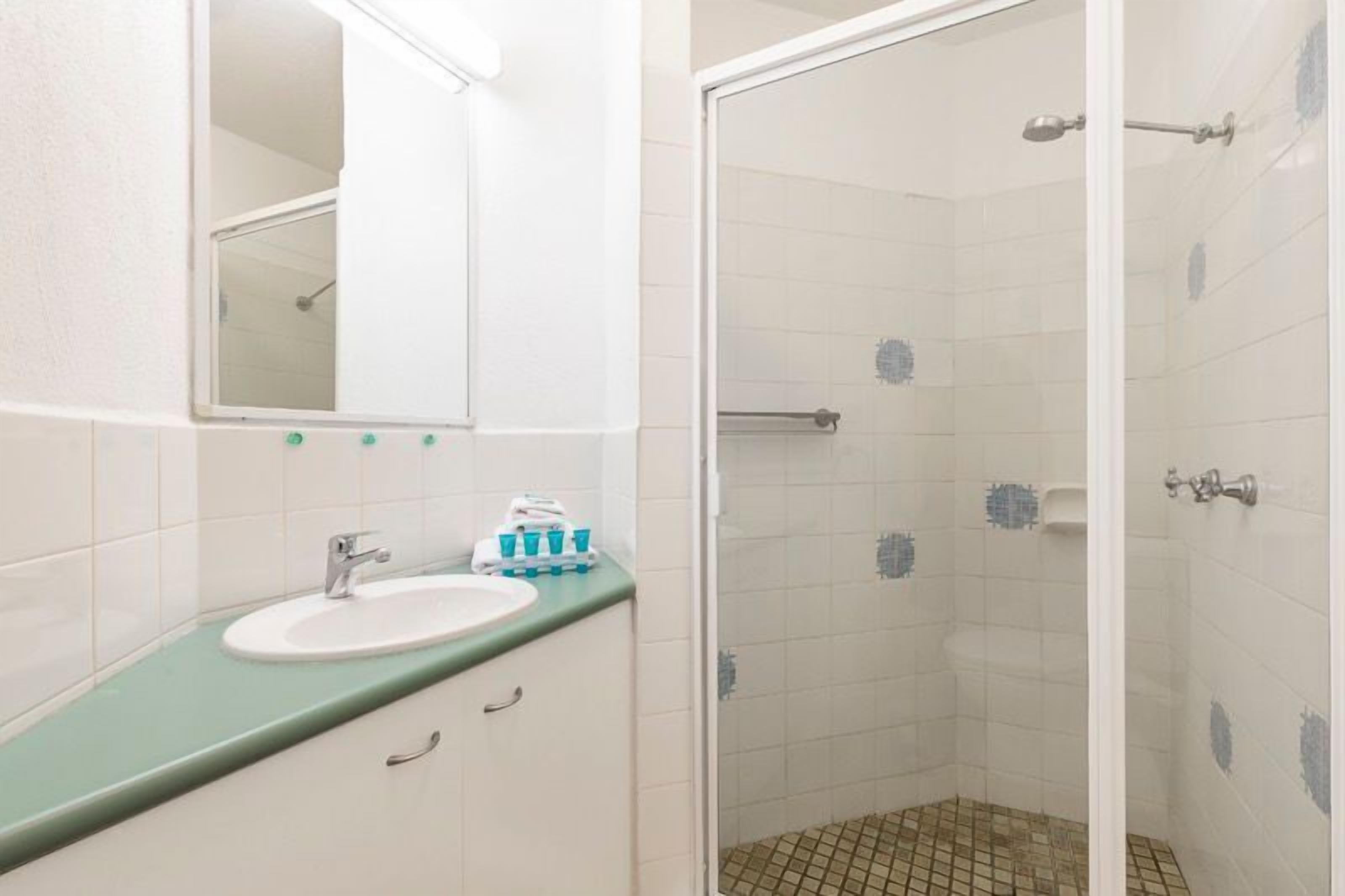A bathroom with a sink, mirror, and shower.