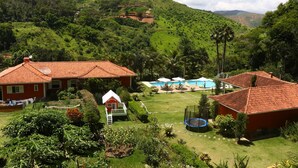 Una propiedad en una ladera con varios edificios de techo rojo, piscina y exuberante vegetación.