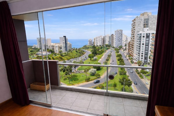 A high-rise apartment with a large balcony, offering a view of a cityscape and a road.