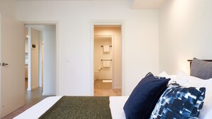 Ein Schlafzimmer mit einem Bett, Kissen, einem Nachttisch und einer Tür zu einem Badezimmer.
