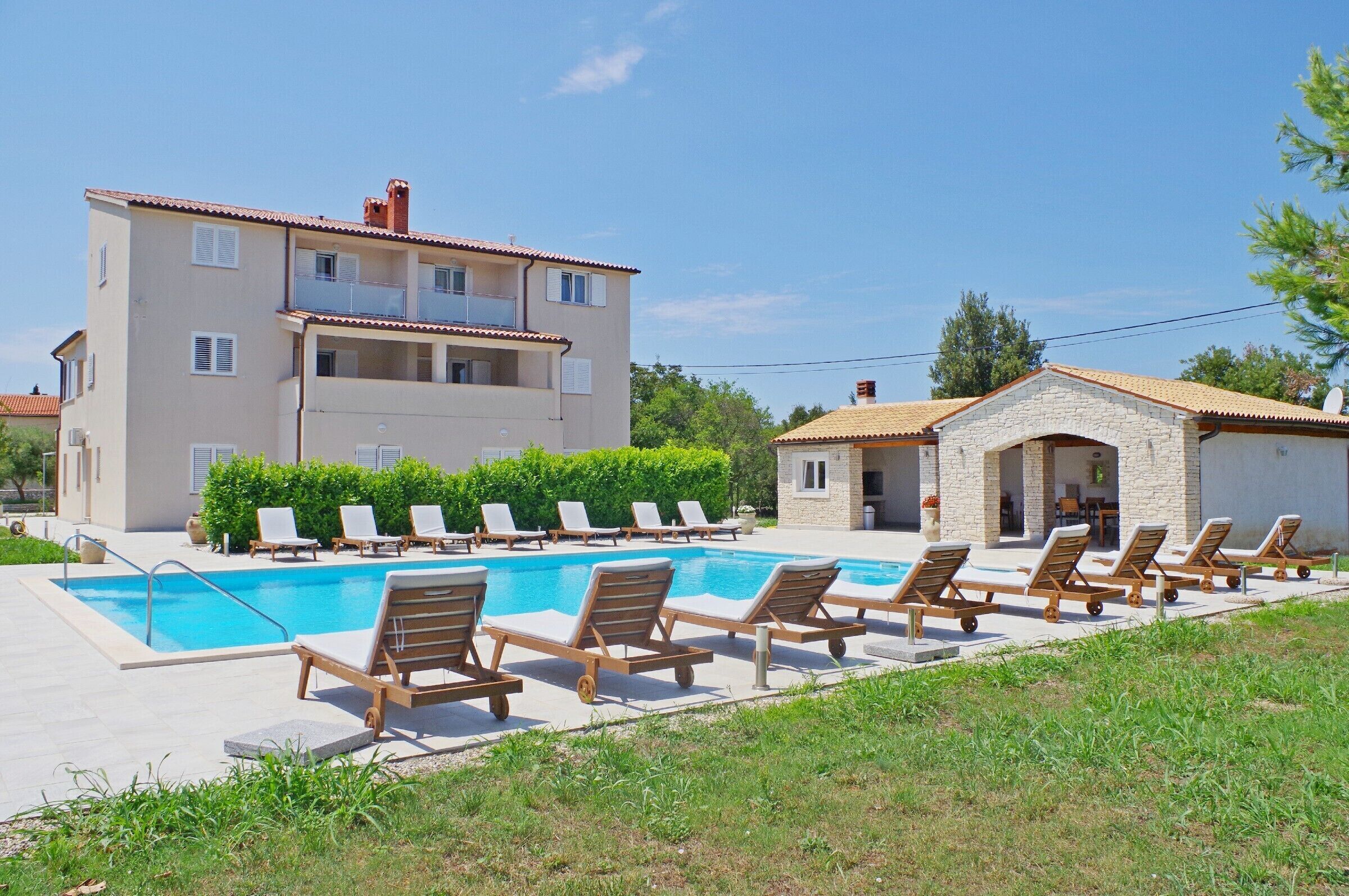 A poolside area with lounge chairs and a building with multiple balconies.
