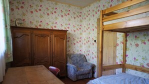 Une chambre avec un lit superposé, une armoire en bois et un papier peint à motifs floraux.
