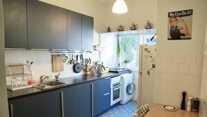 Cocina con armarios oscuros, un lavamanos, una estufa y una lavadora. Hay una ventana con vistas a zonas verdes.