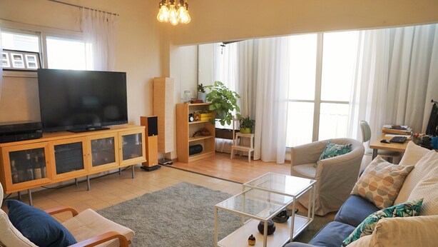 Una sala de estar con televisión, sofá, sillón, mesa de centro y estantería.