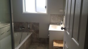 Un baño con ducha, lavamanos y ventana.