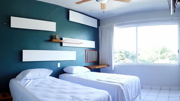 A room with two beds, a ceiling fan, and a large window. - Xcaret. cómodo apartamento muy bien equipado. (Merida)