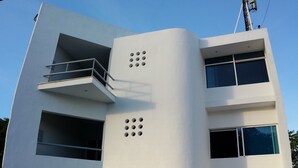 A modern multi-story building with a flat roof, large windows, and a balcony. - Xcaret. cómodo apartamento muy bien equipado. (Merida)