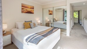 Ein Schlafzimmer mit einem großen Bett, einem Nachttisch mit Lampe, einem Spiegel und einem Bild an der Wand.