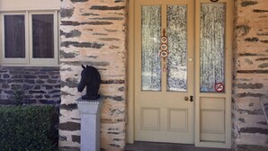 A stone house with a yellow door, a horse statue, and a no parking sign.
