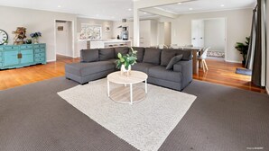 Una sala moderna con un sofá seccional gris, una mesa de centro blanca y un mueble turquesa.