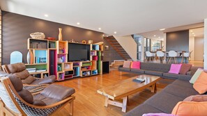 Un salon moderne comprenant un canapé, une table basse, une bibliothèque et un téléviseur.