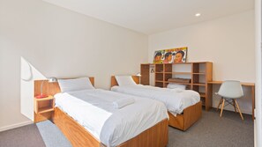 Une chambre d’hôtel avec deux lits, un bureau, une chaise, une armoire et un tableau au mur.