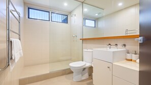 Une salle de bain moderne avec une douche à parois de verre, des toilettes et un lavabo avec un miroir au-dessus.