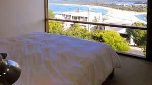 Une chambre avec une grande fenêtre donnant sur une plage et des bâtiments.