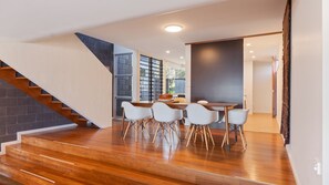 Un intérieur moderne avec un escalier, un coin repas et une vue sur l’extérieur.
