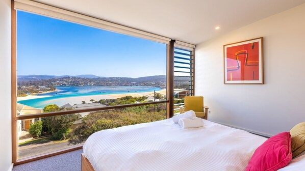 Une chambre avec une grande fenêtre donnant sur une plage et sur le paysage urbain.