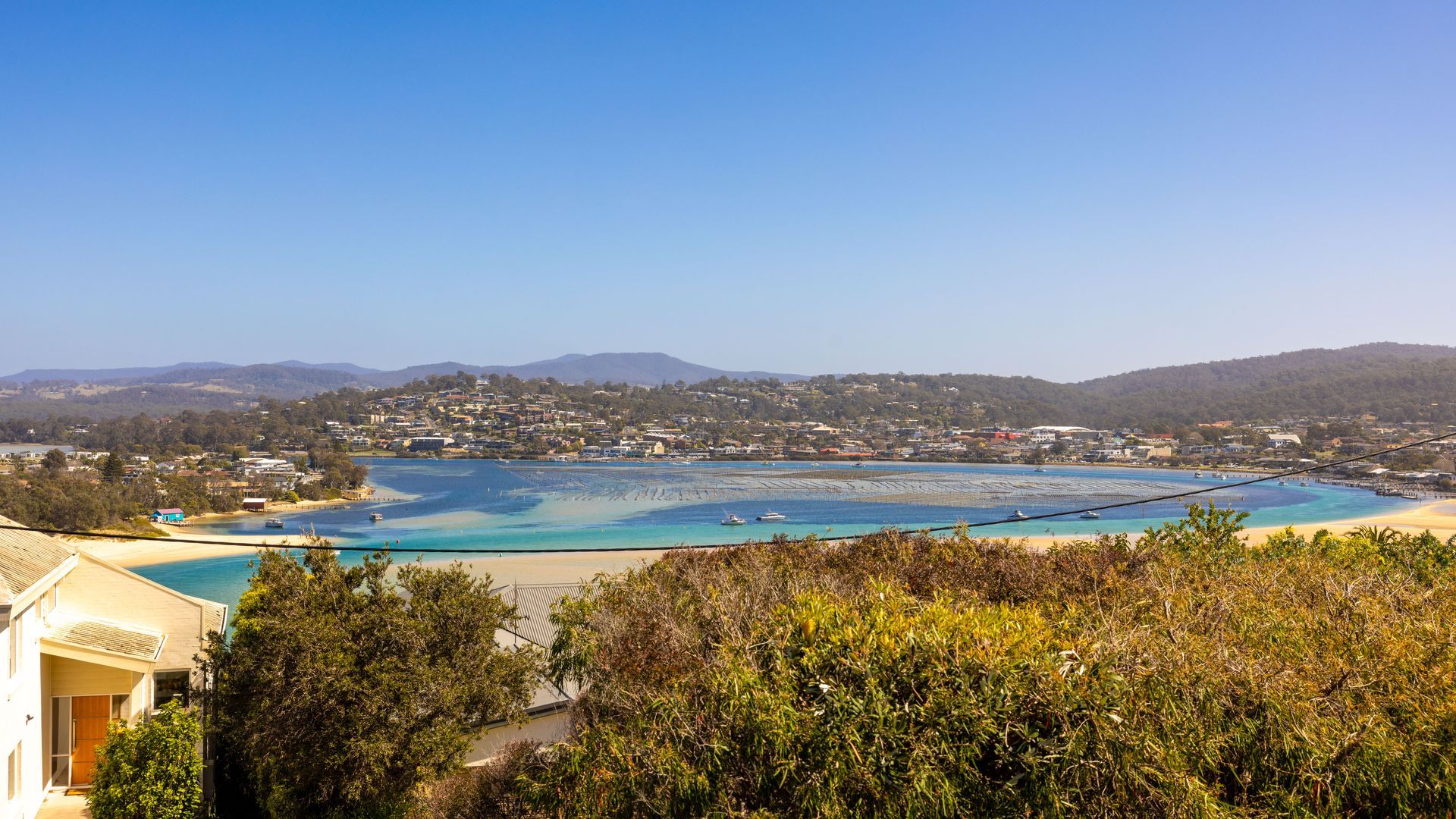 A coastal town with a clear view of the sea, a beach, and a residential area with houses.