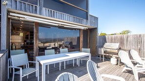 Une terrasse extérieure avec une table et des chaises, un barbecue et une vue sur le paysage environnant.