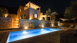 Ein modernes Haus mit Swimmingpool, Steinmauern und Sitzgelegenheit im Freien.