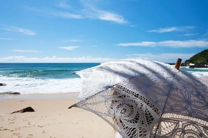 En strand med en hvid hæklet strandparasol.