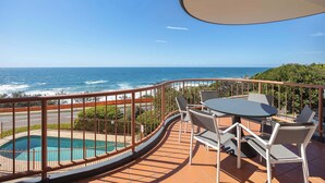 Un balcon avec piscine, un espace salon extérieur et une vue sur l’océan.