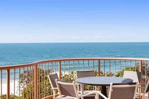 Varanda com mesa e cadeiras com vista para o oceano.