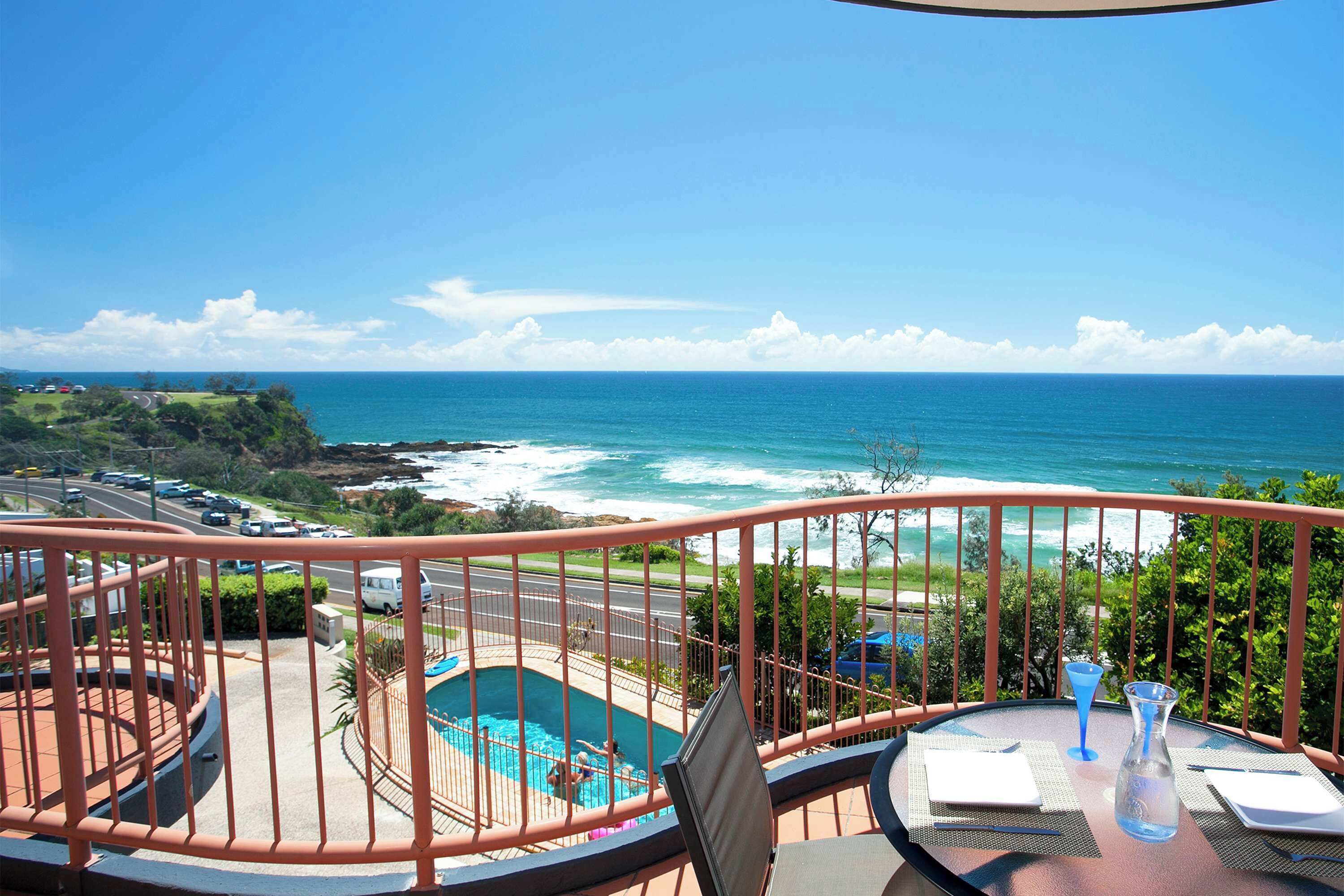 A balcony with a view of the ocean and a swimming pool.