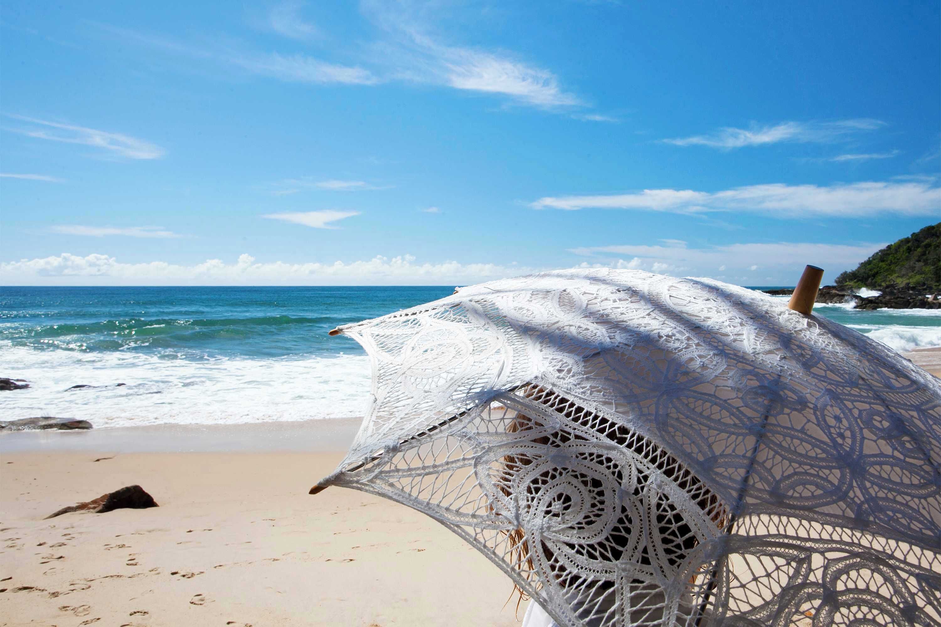Une plage avec un parasol de plage blanc en crochet.