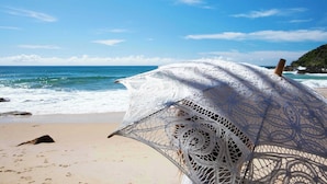 Une plage avec un parasol de plage blanc en crochet.