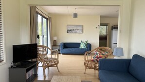 Ein Wohnzimmer mit Fernseher, zwei Sofas, einem Couchtisch und einem Bücherregal.