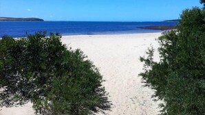 Ein Strand mit freiem Blick auf das Meer und das entfernte Ufer.