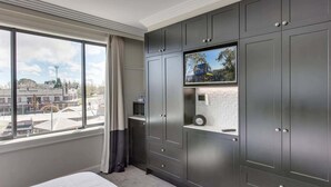 A hotel room with a large bed, a TV mounted on a cabinet, and a view of the city through a large window. - Perfect Located 2-Bed Blue Mountains Getaway (Katoomba)