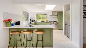 A modern kitchen with a central island, bar stools, and a view of the backyard. - Newly Renovated with aircon throughout! Family, Horse and Dog Friendly Getaway (Congewai)