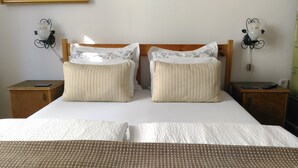 Una cama bien hecha con dos almohadas, un cabecero de madera y dos mesitas de noche con lámparas.